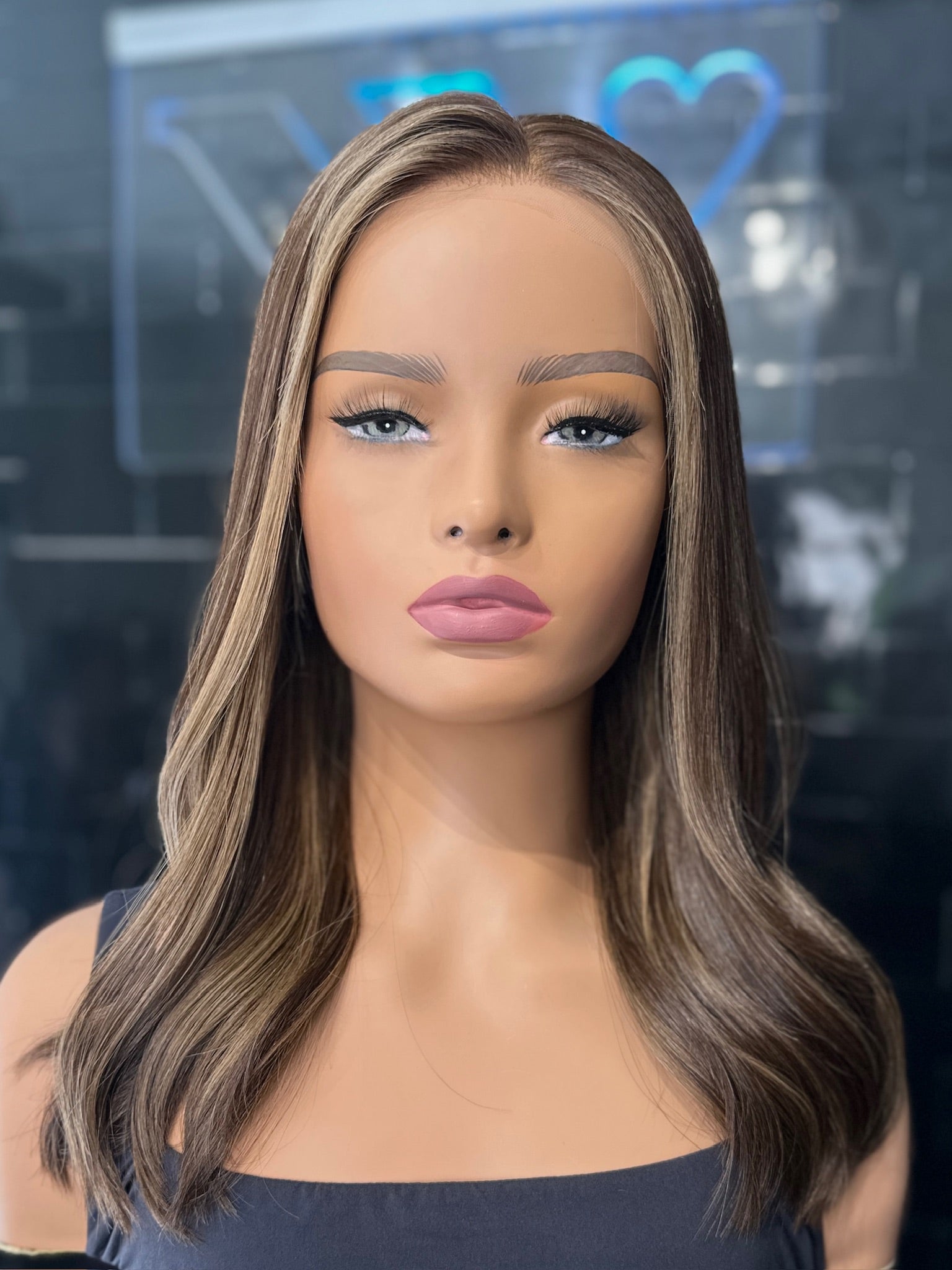 A 22 inch long layer cut wig with a neutral medium brown base and baby lights, displayed on a mannequin head.