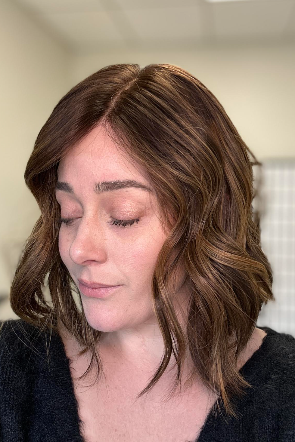 Woman with shoulder-length wavy hair in a neutral indoor setting